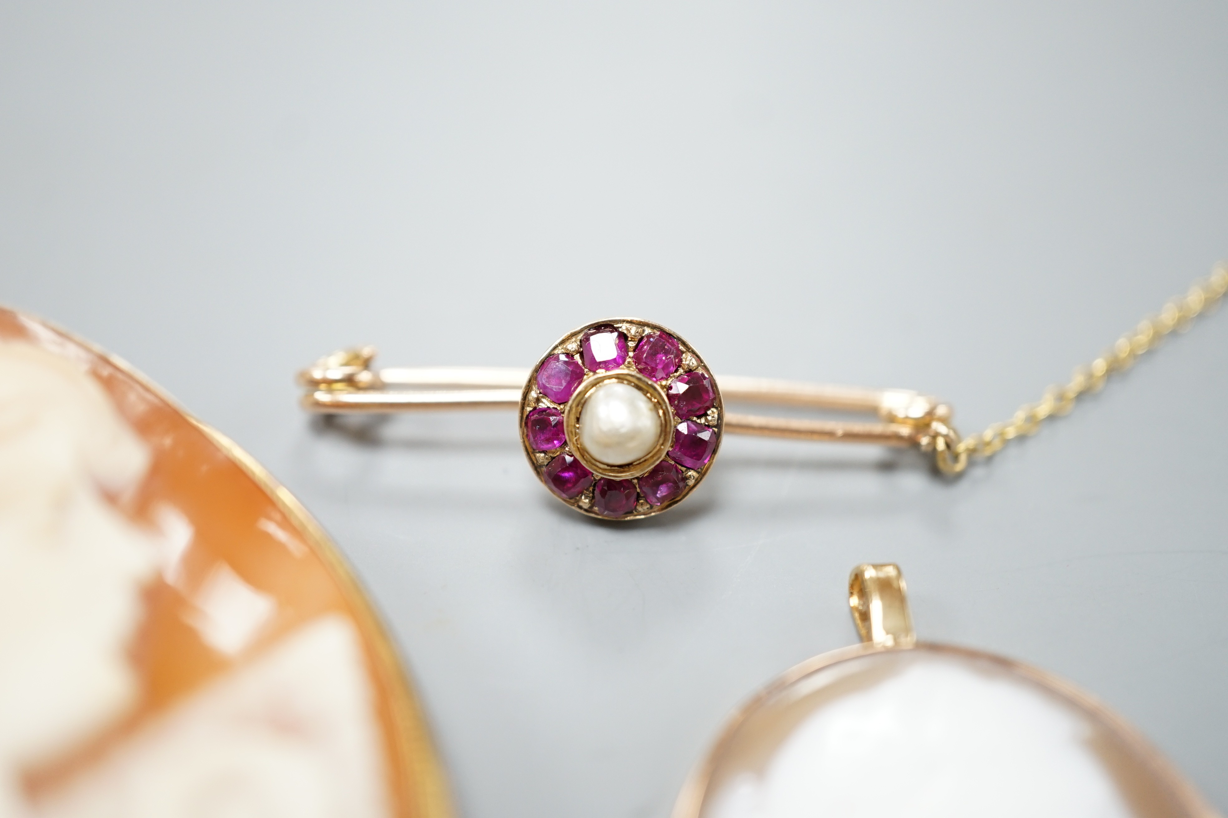 A 9ct mounted oval cameo shell pendant, 36mm, a similar gilt white metal mounted brooch and a yellow metal, ruby and cultured pearl cluster set bar brooch(converted).